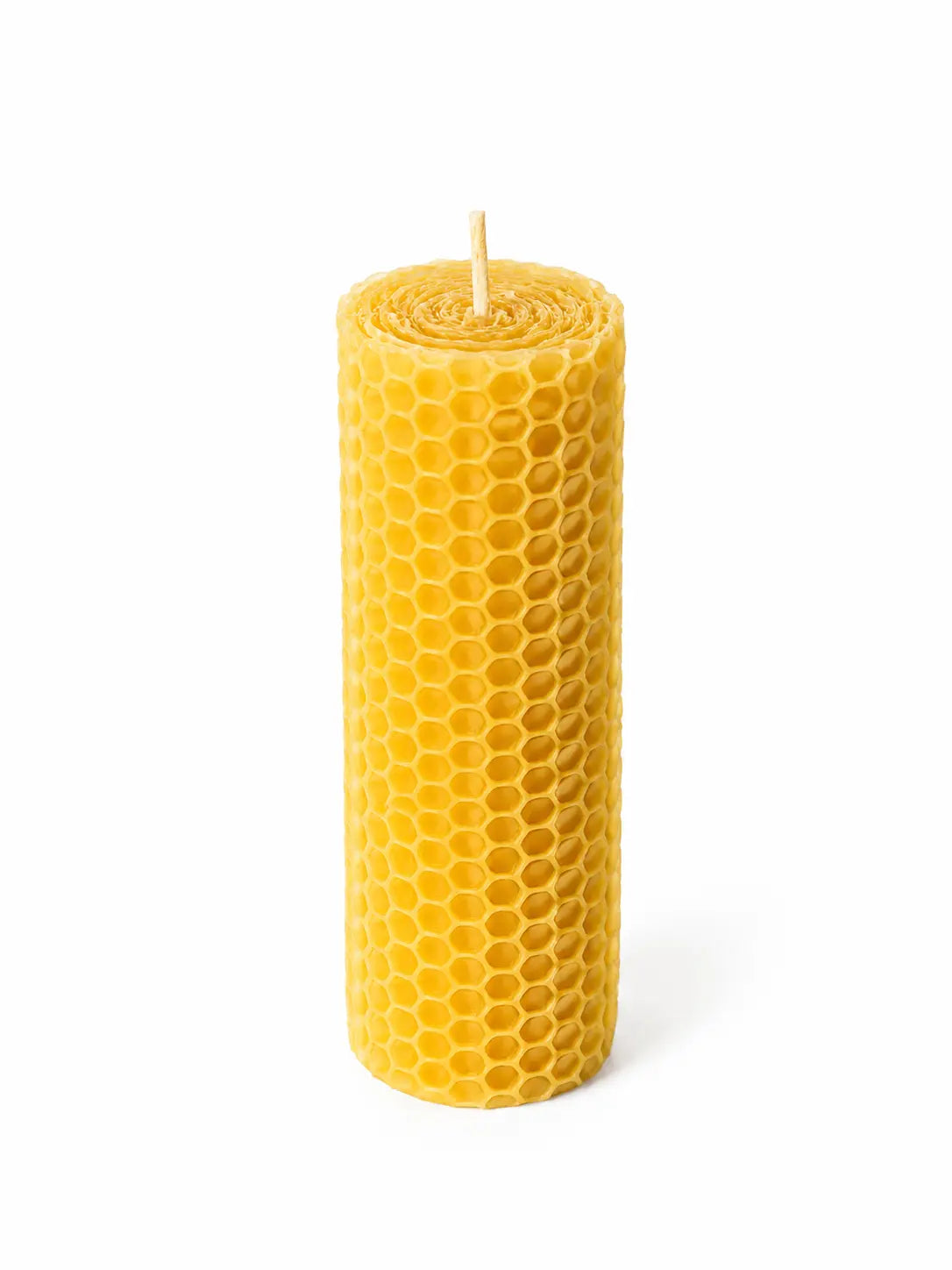 Primer plano de una vela artesanal de cera de abeja natural encendida, mostrando su característica textura de panal de abeja y una llama cálida.