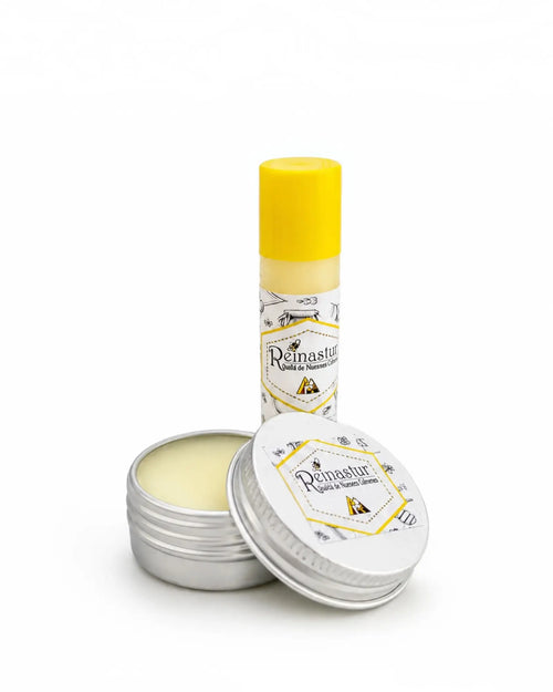 Bálsamo labial natural de Reinastur presentado en sus dos formatos disponibles: barra en tubo giratorio y cajita de lata metálica redonda.