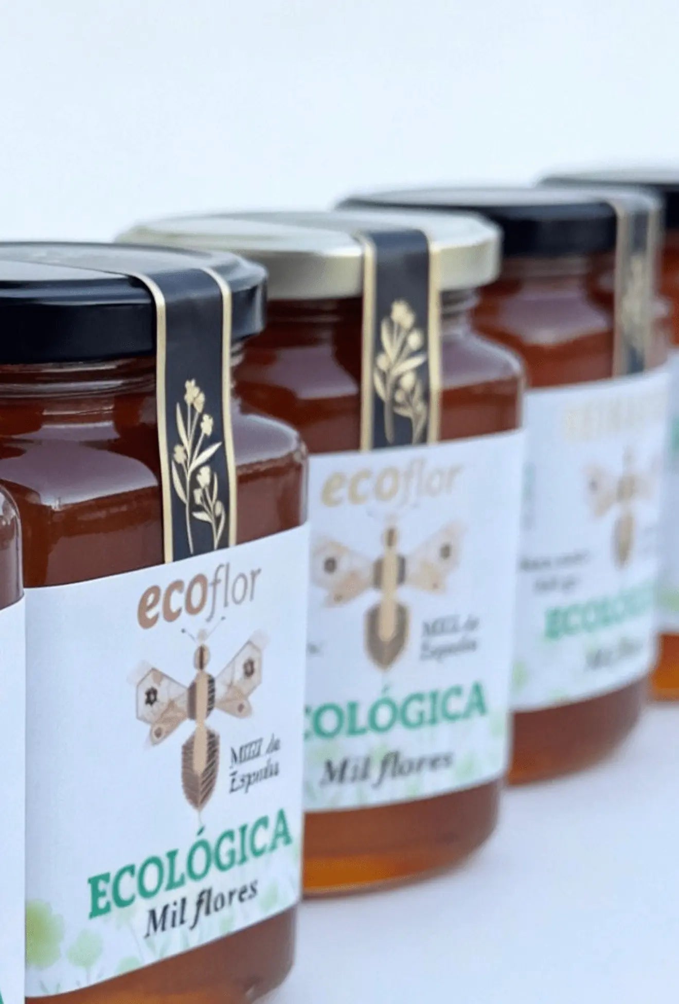Hilera en perspectiva de tarros de miel ecológica de Milflores de la marca Ecoflor enfocando el primer plano.