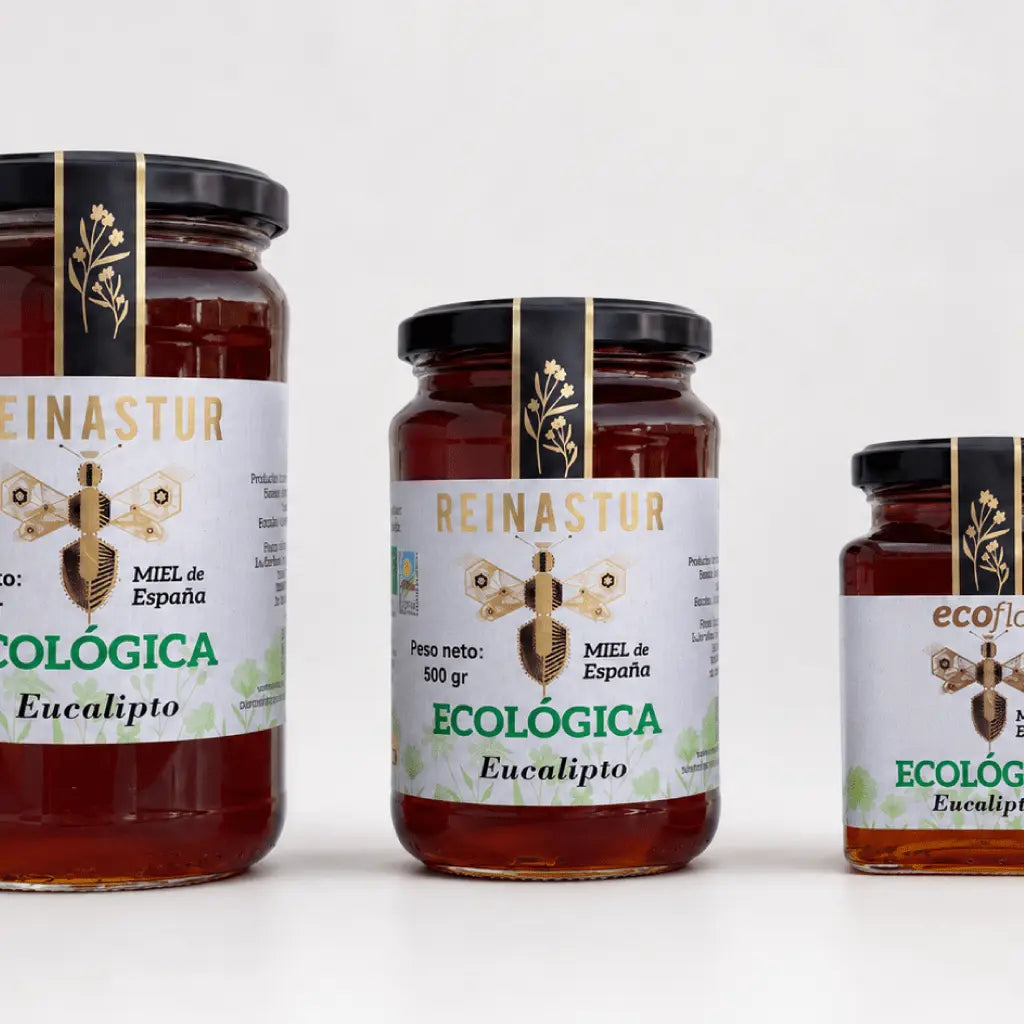 Primer plano detallado de tres tarros de miel ecológica de Eucalipto mostrando las etiquetas y el color ámbar intenso del producto.